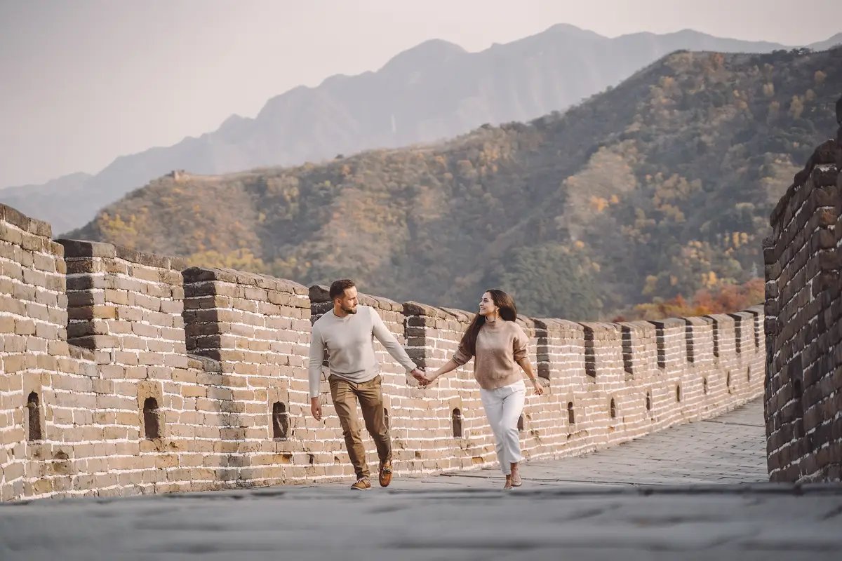 Beautiful young couple running and jumping at the Great Wall of China.