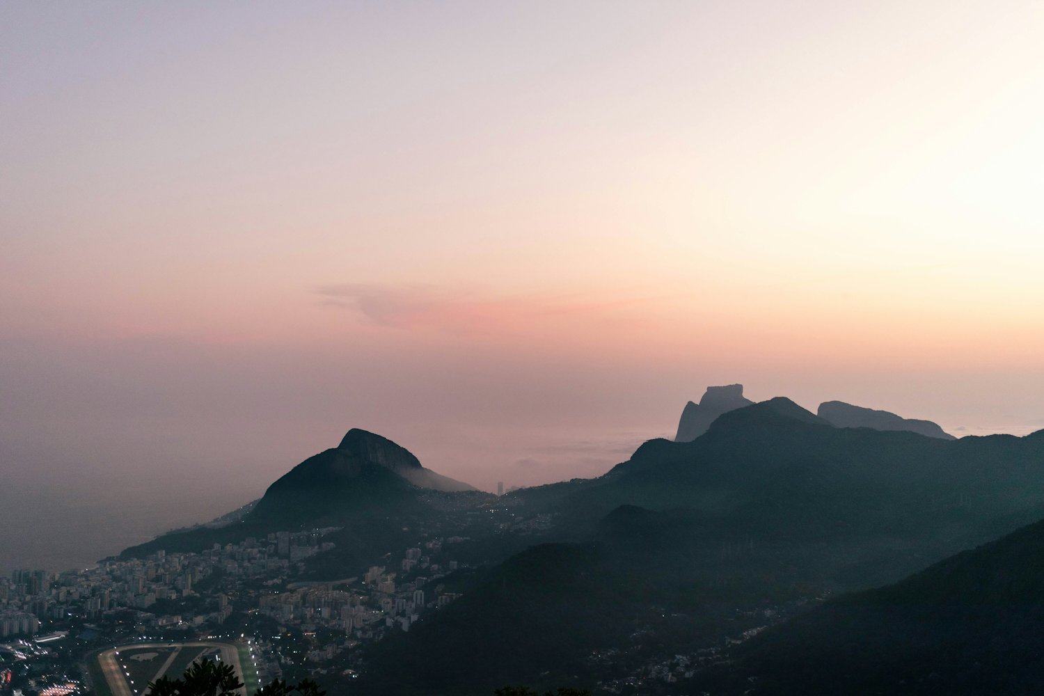Sunset panorama over Rio de Janeiro's mountains and hidden viewpoints, with Pedra da Gávea in the distance