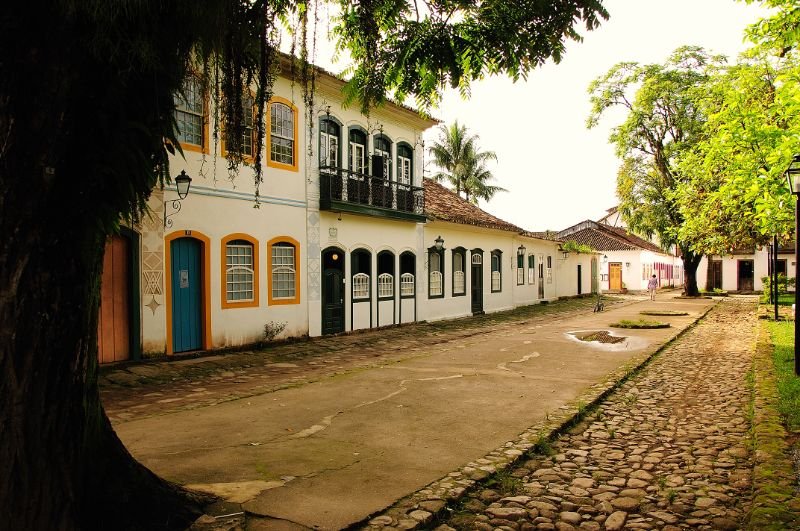 Praia paradisíaca com água cristalina azul, areia branca e coqueiros sob céu claro ensolarado